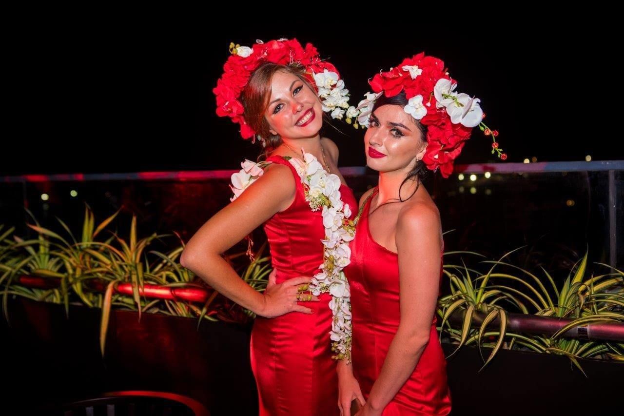 Two beautiful ladies wearing red dresses and floral hats at The Kingsbury Hotel