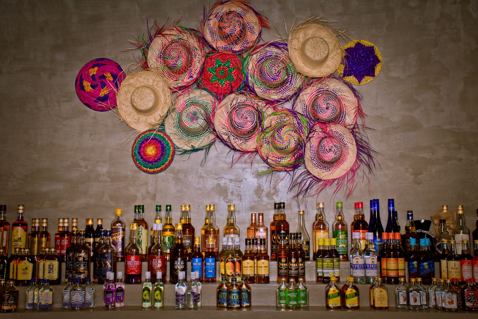 Arrack bottle collection with colorful hats decorating the wall at the Taven bar