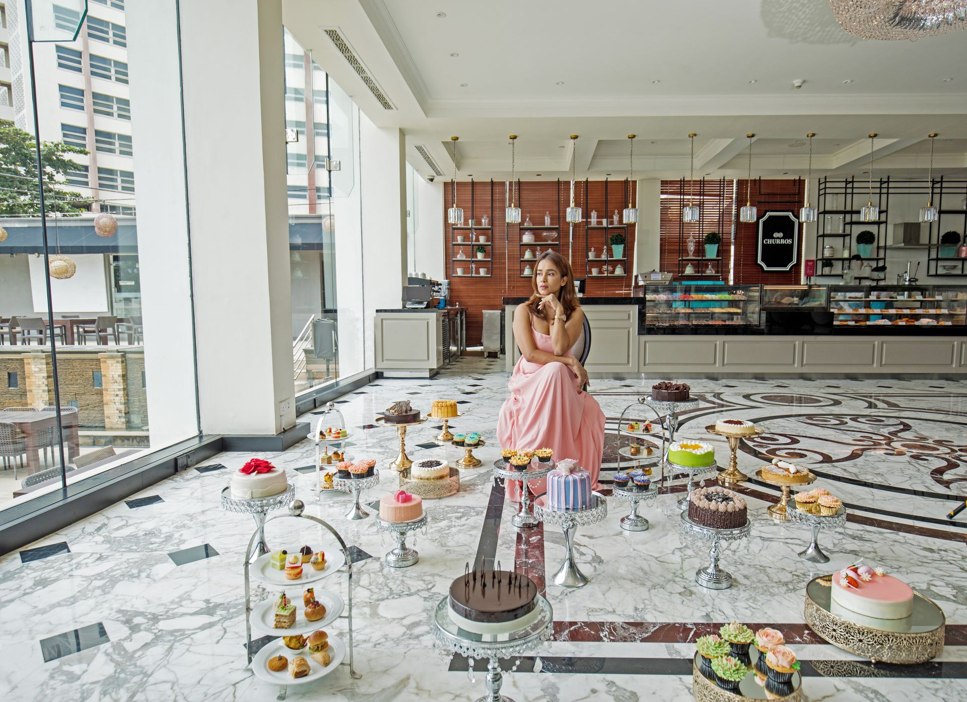 Lady sitting in front of a variety of cakes at The Kingsbury Hotel