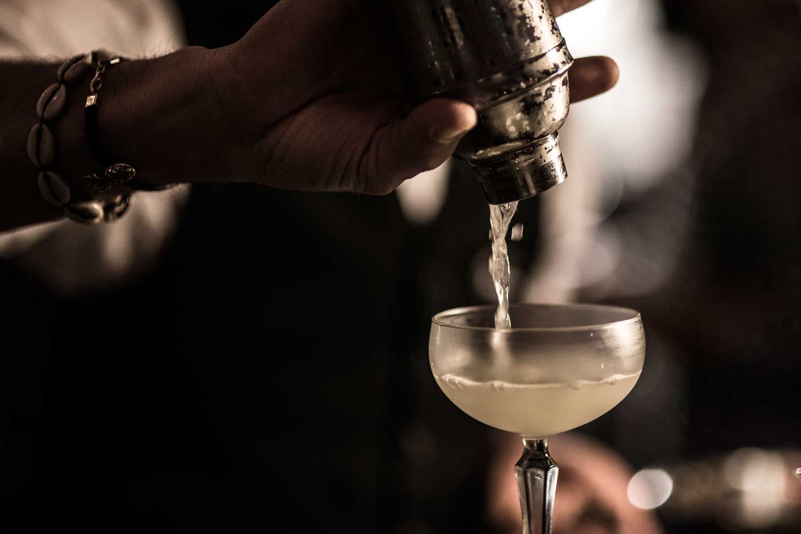 Mixologist pouring a cocktail drink into a glass at The Kingsbury Hotel