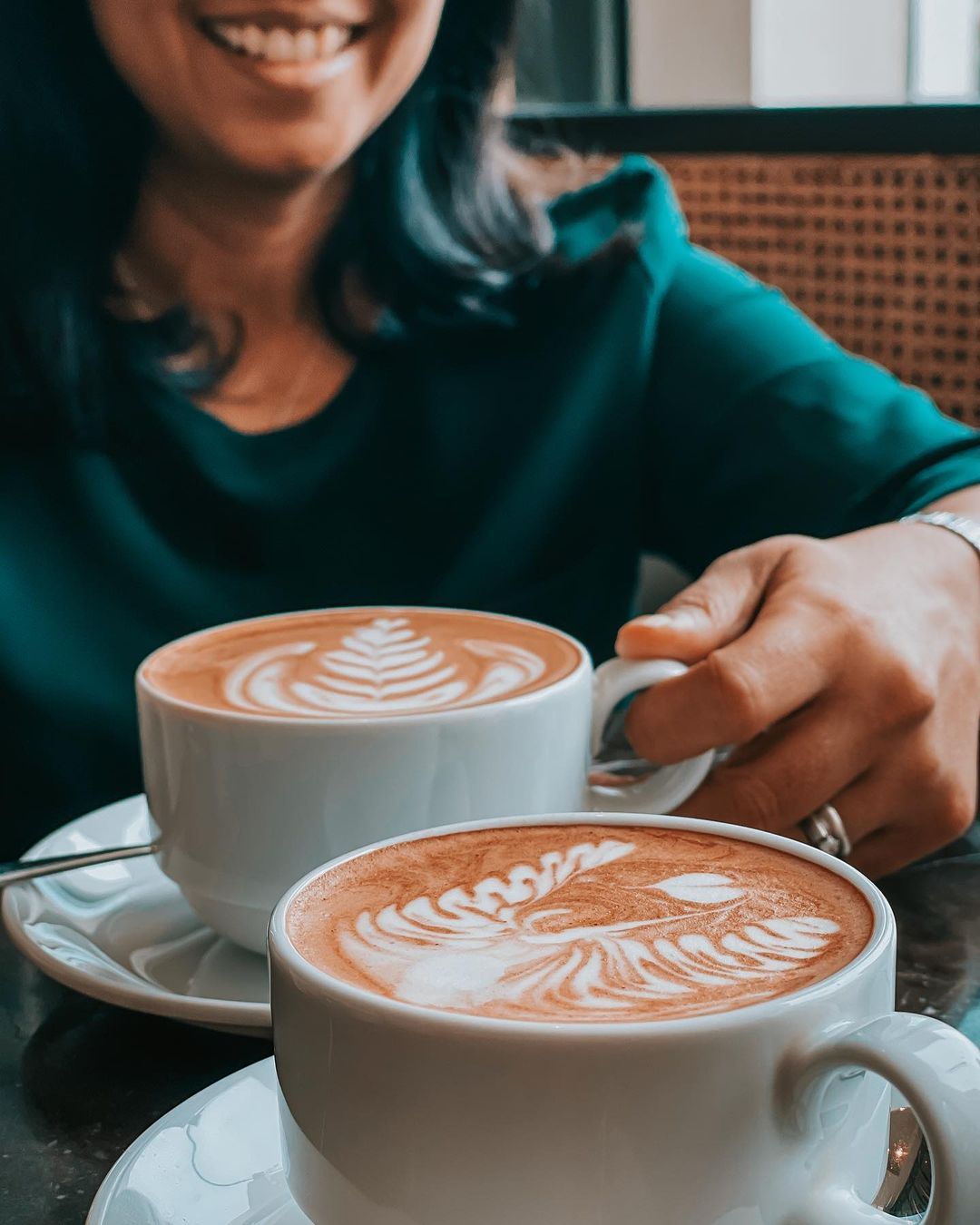Couple enjoying two cups of cappuccino with coffee art at The Kingsbury Hotel