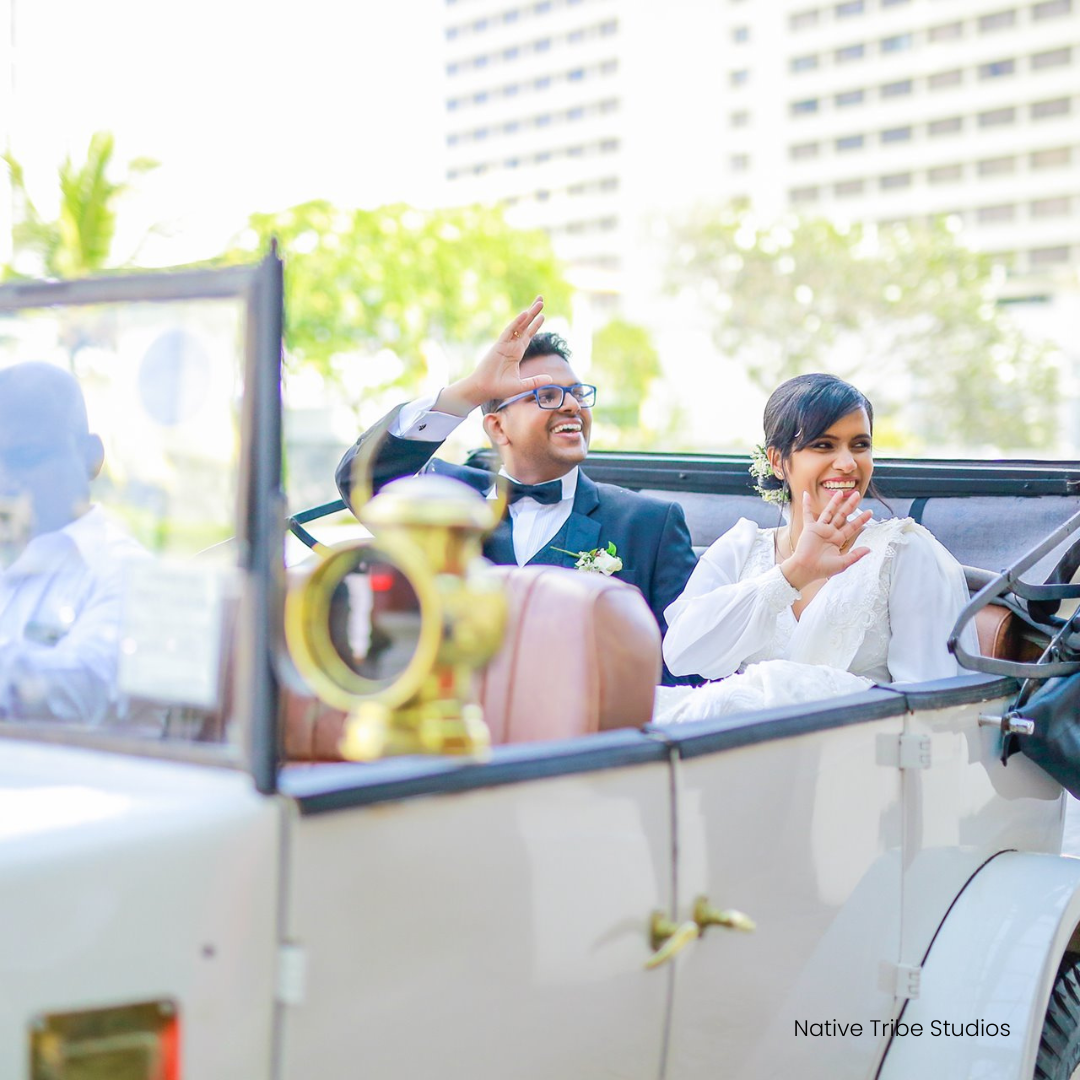 Wedded couple leaving The Kingsbury Hotel in a white vintage car