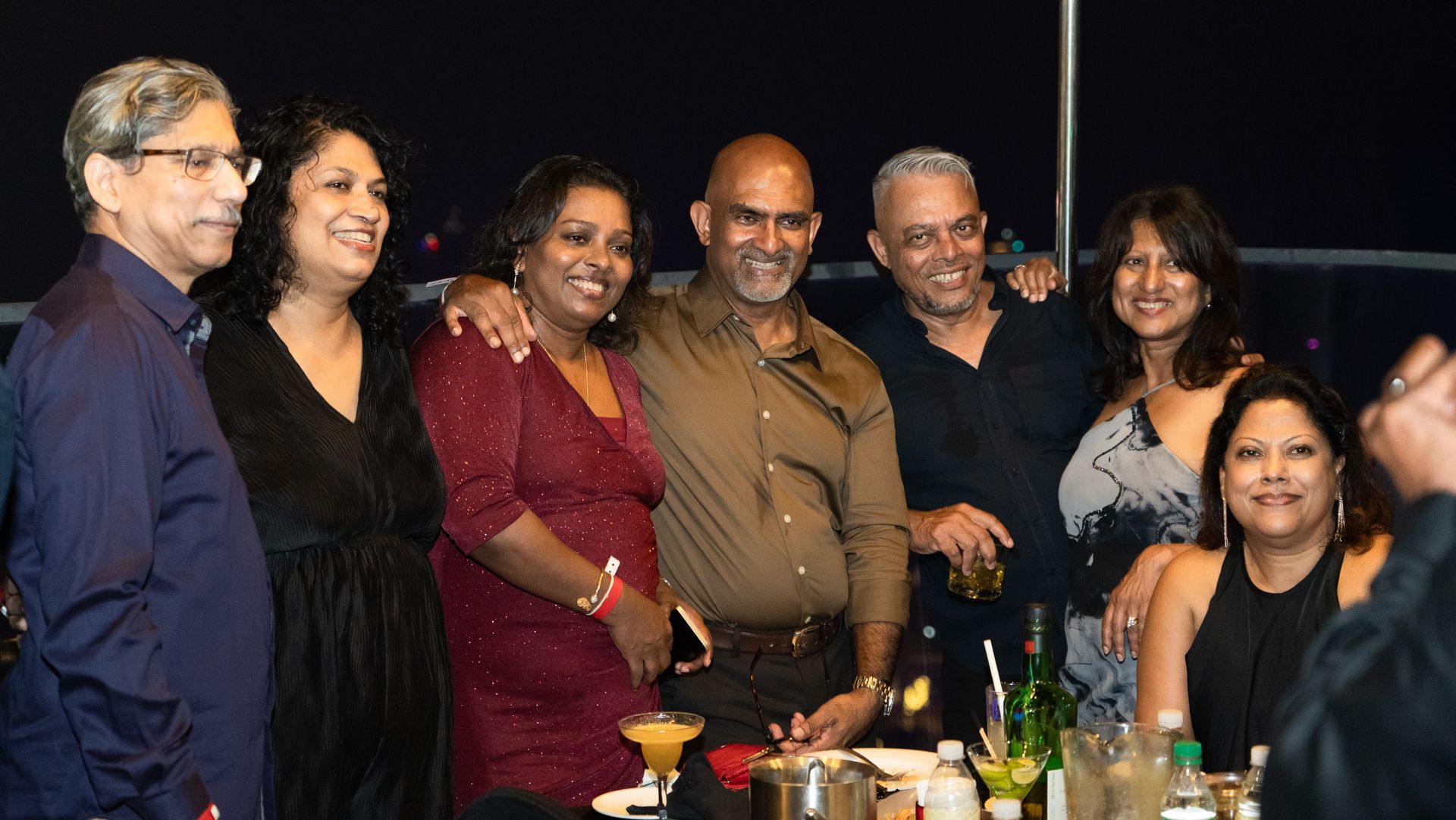Three adults smiling and posing together at a nighttime social gathering