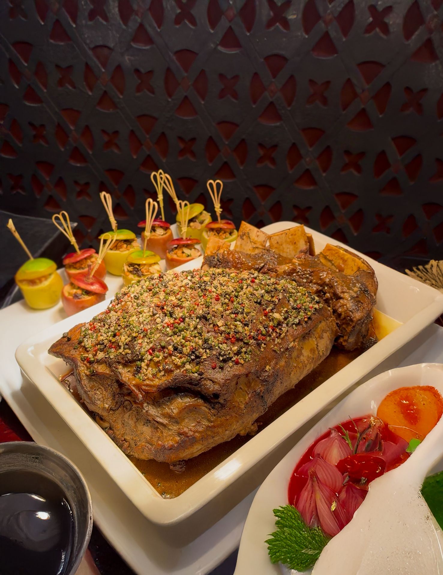 A roasted meat dish topped with dried herbs and coarse pepper seasoning