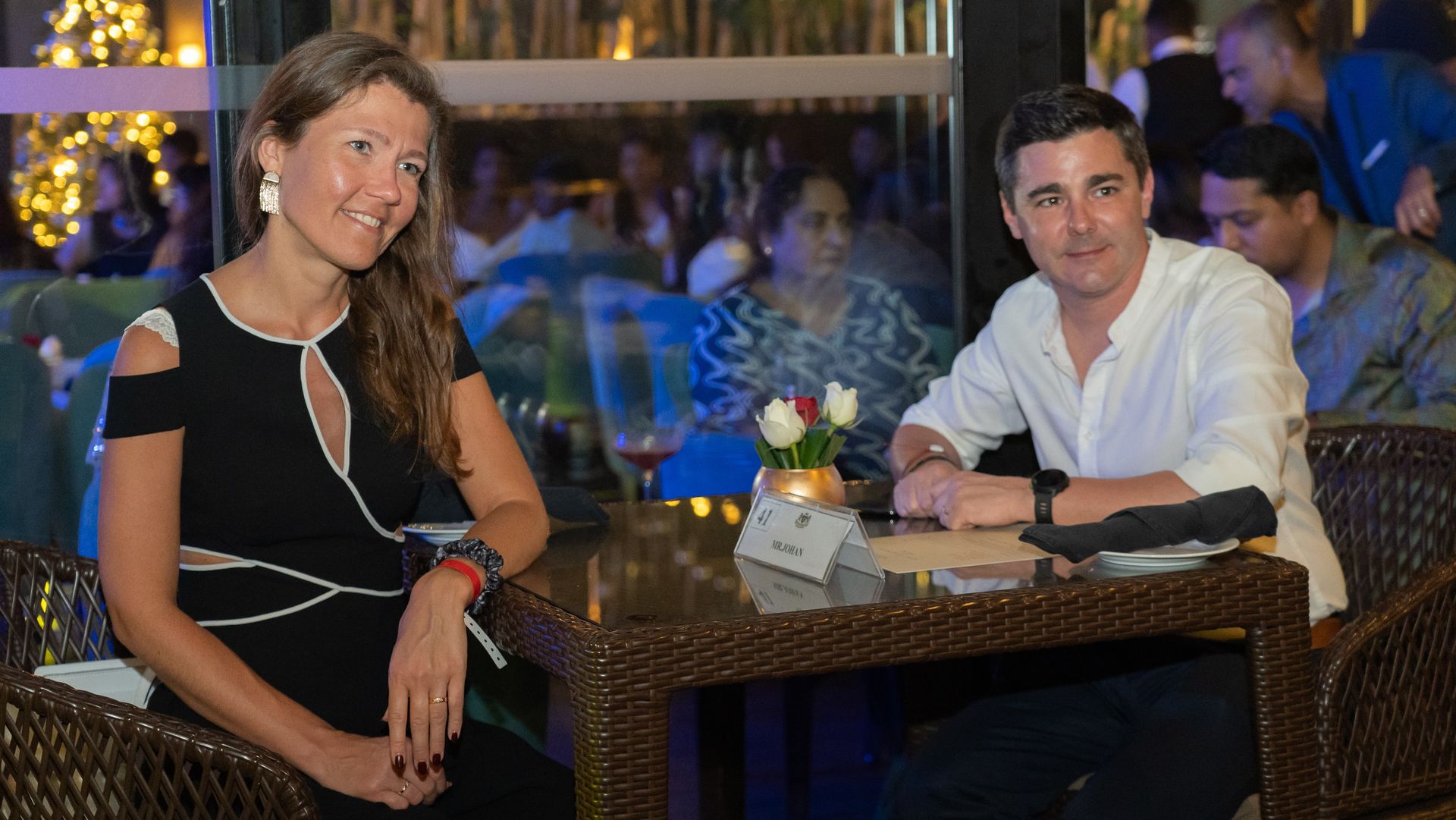 Two people are sitting at a modern, wicker-style table.